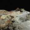Tan-coloured elpidite alongside a prismatic bundle of leifite